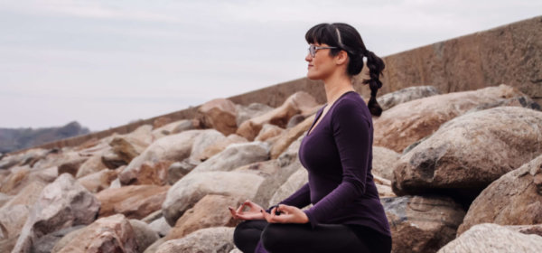 Kvinna sitter på stenar och mediterar